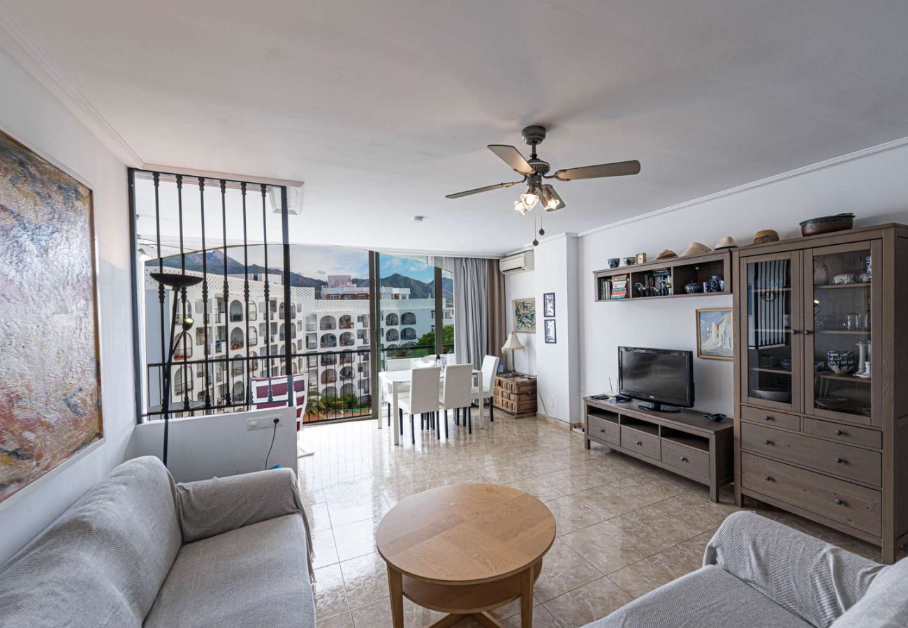 Heller Wohnraum mit Sofa und Fernseher in einer Ferienwohnung für 4 Personen in Nerja