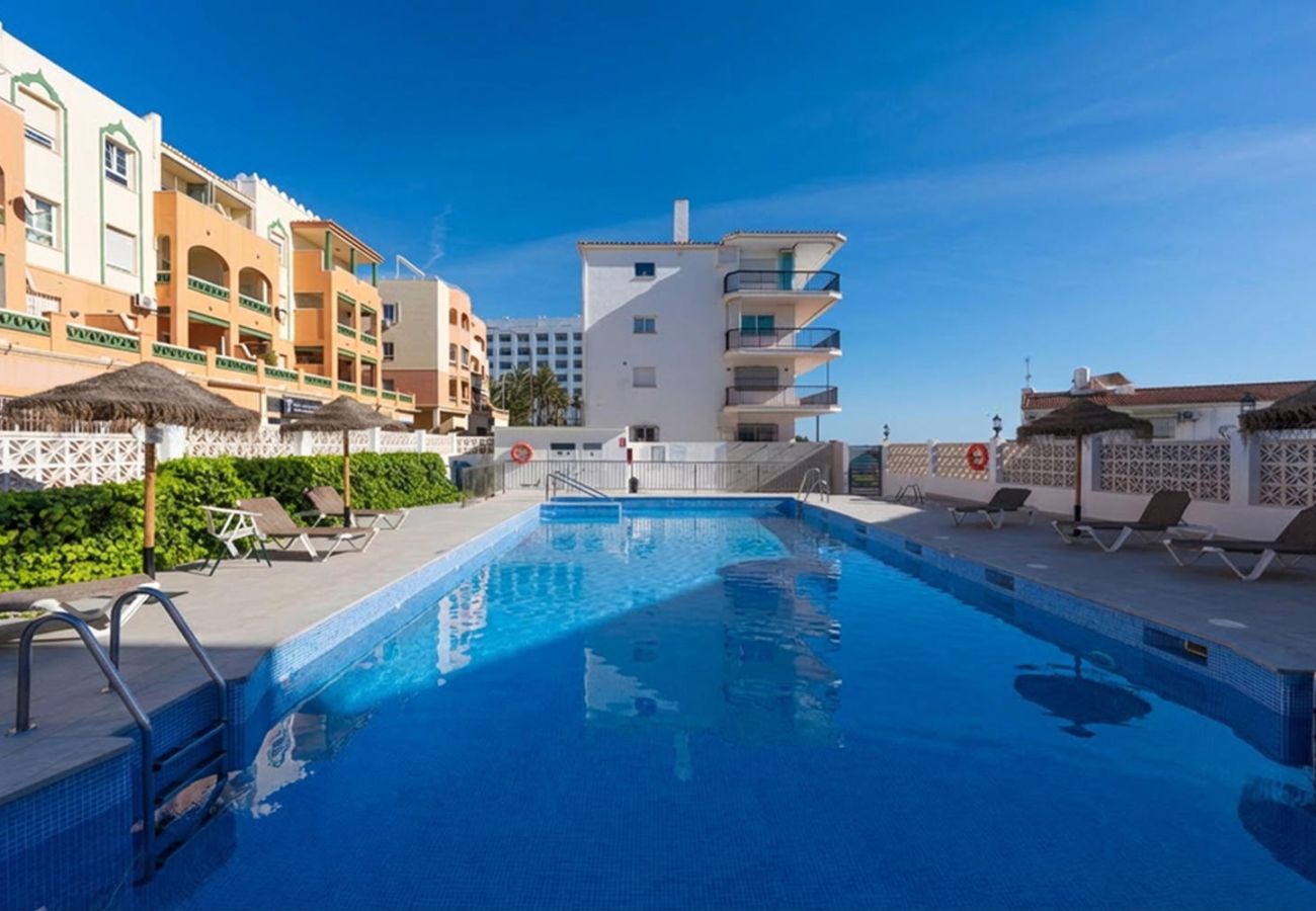 Gemeinschaftspool des Arce 5 Gebäudes mit Sonnenschirmen und Liegestühlen.