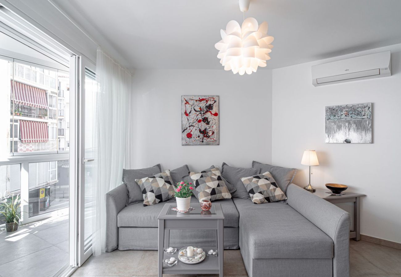 Helles Wohnzimmer mit Designersofa und direktem Zugang zum verglasten Balkon im Zentrum von Nerja.