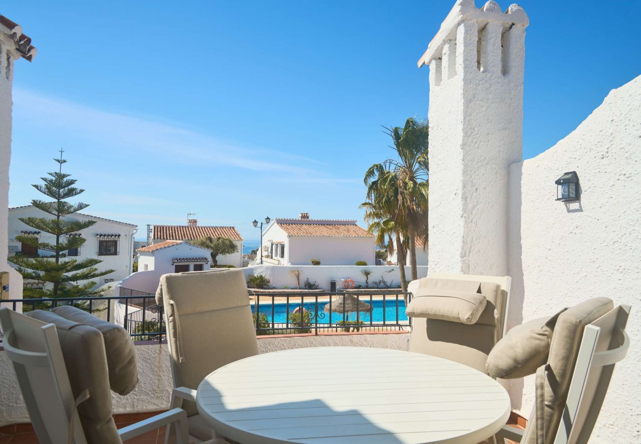 Private Terrasse im Capistrano Village Nerja mit Esstisch und Blick auf den Gemeinschaftspool.